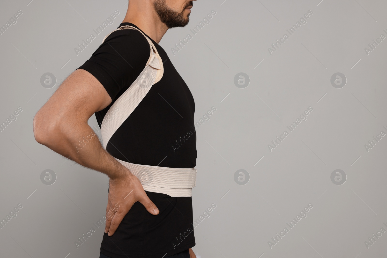 Photo of Closeup view of man with orthopedic corset on grey background, space for text