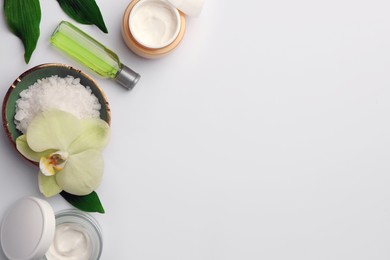 Flat lay composition with different spa products and beautiful flower on white table. Space for text