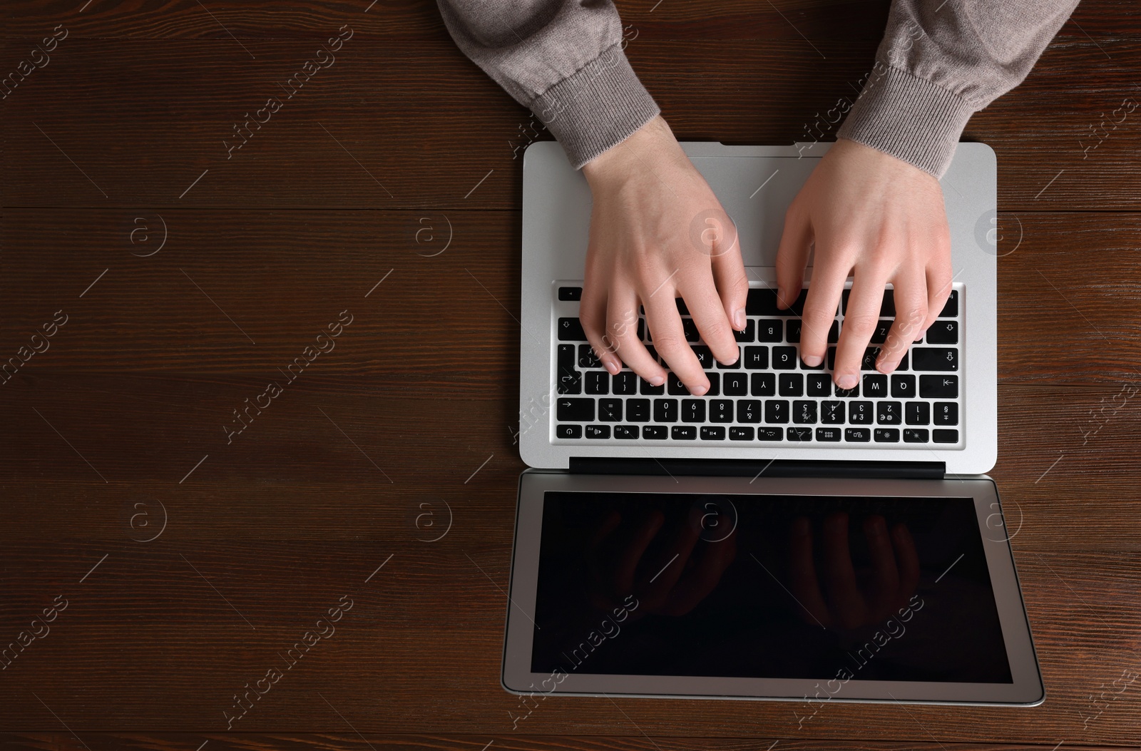 Photo of Man working with laptop at wooden table, top view. Space for text