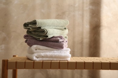 Stack of soft towels on wicker bench indoors