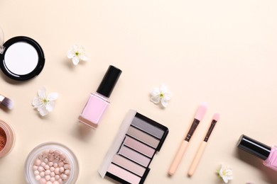 Photo of Flat lay composition with different makeup products and beautiful spring flowers on beige background, space for text