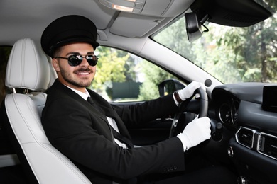 Photo of Young handsome driver in luxury car. Chauffeur service