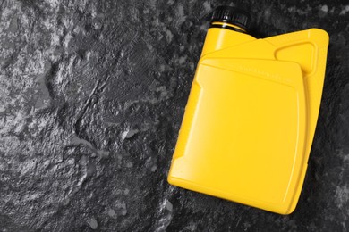 Motor oil in yellow canister on black table, top view. Space for text