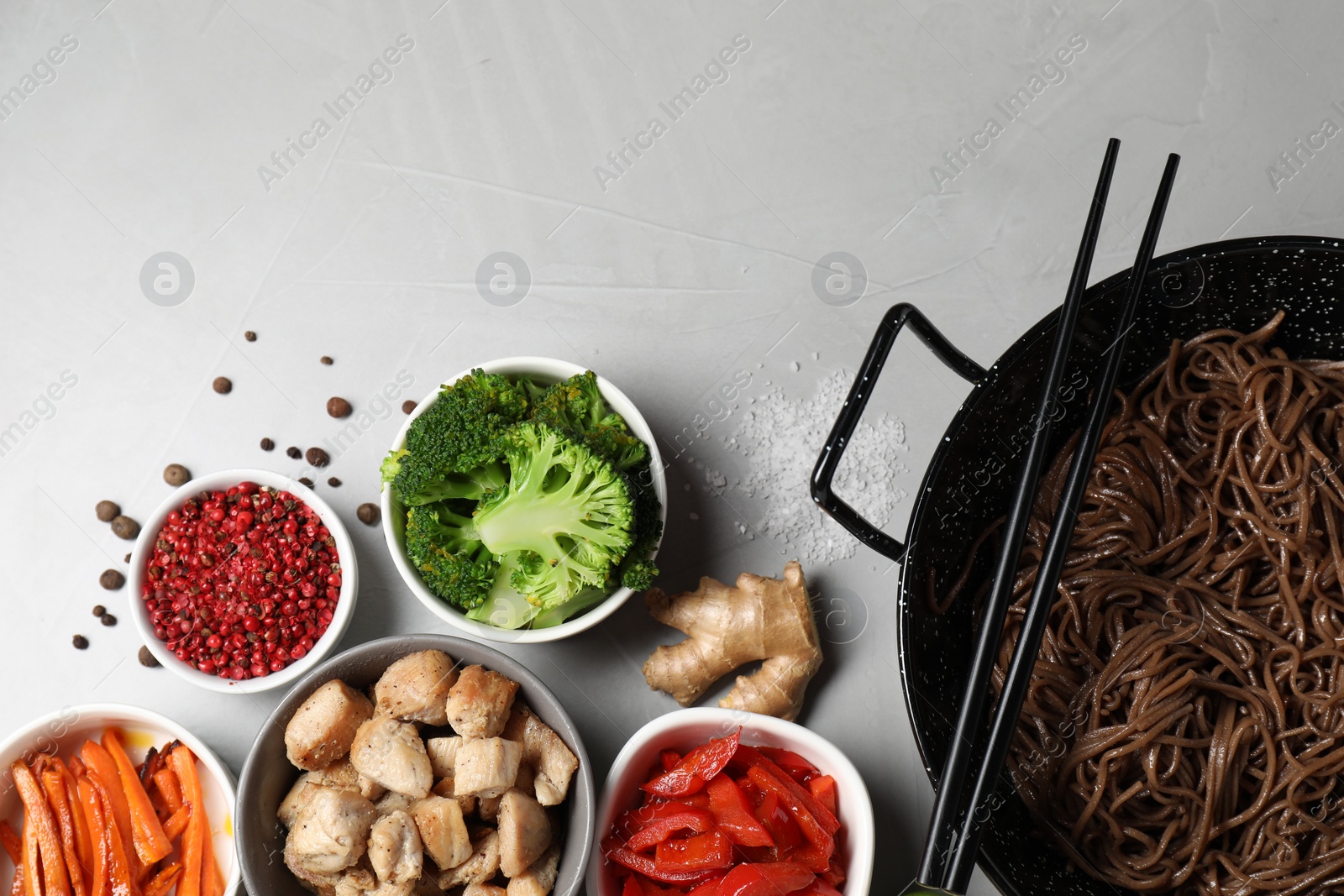 Photo of Wok with noodles, chicken and other products on light grey table, flat lay