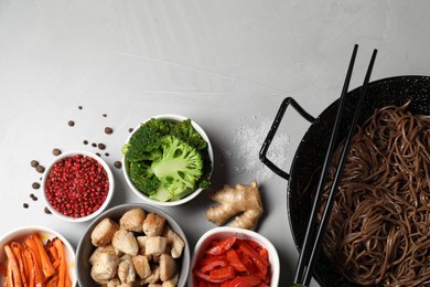 Photo of Wok with noodles, chicken and other products on light grey table, flat lay