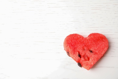 Photo of heart shaped watermelon slice on white wooden background, top view