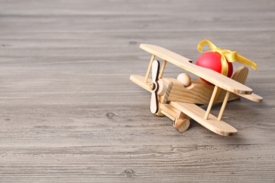 Wooden airplane with Easter egg on table, space for text