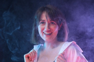 Photo of Portrait of happy woman in smoke on dark background