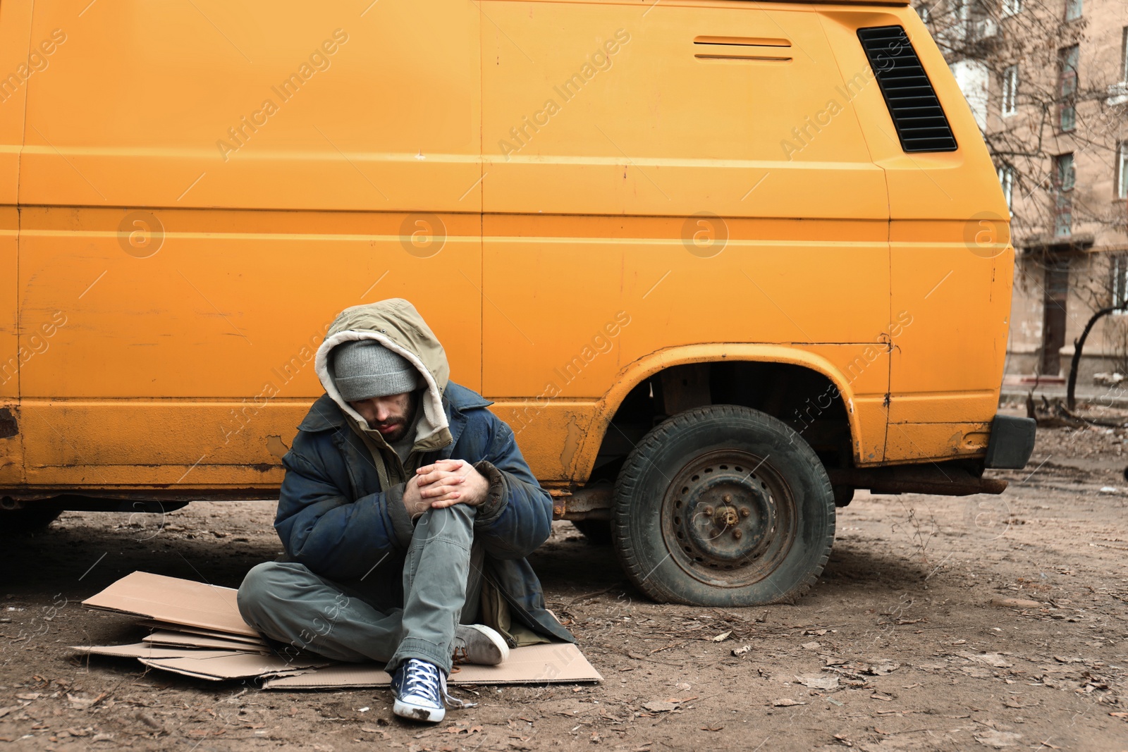 Photo of Poor homeless man sitting near van outdoors