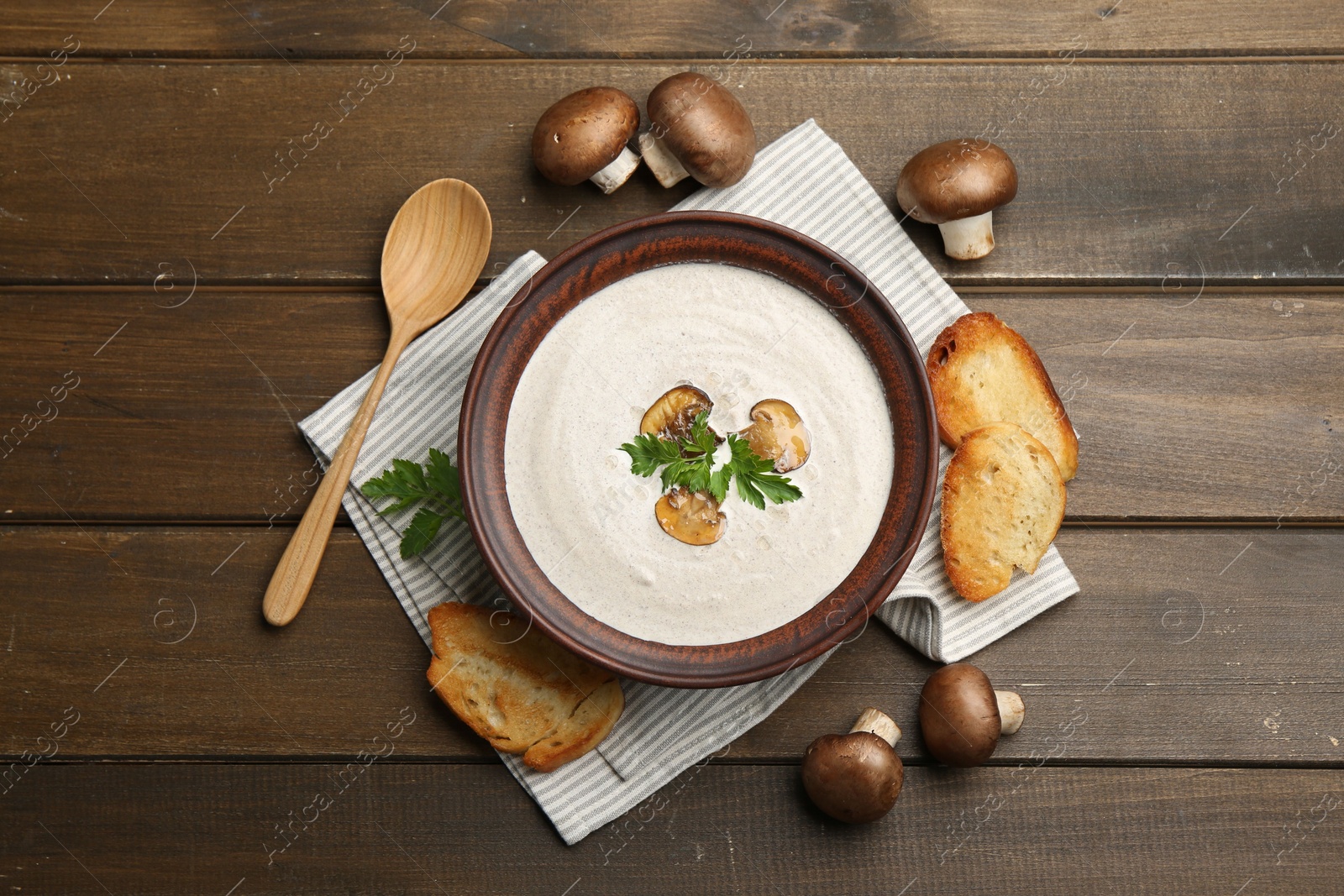 Photo of Fresh homemade mushroom soup served on wooden table, flat lay