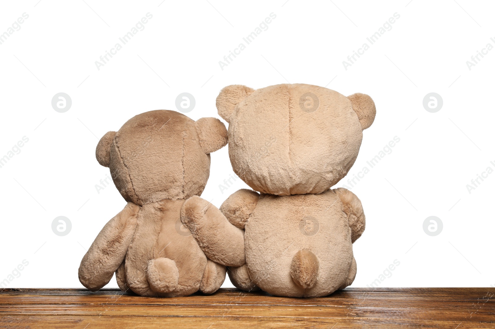 Photo of Cute teddy bears on wooden table against white background, back view