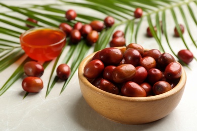 Photo of Palm oil fruits in bowl on white table, closeup