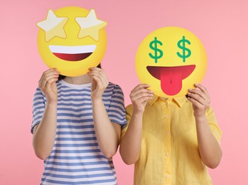 Photo of People covering faces with emoticons on pink background