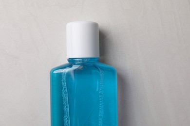 Fresh mouthwash in bottle on grey textured background, top view