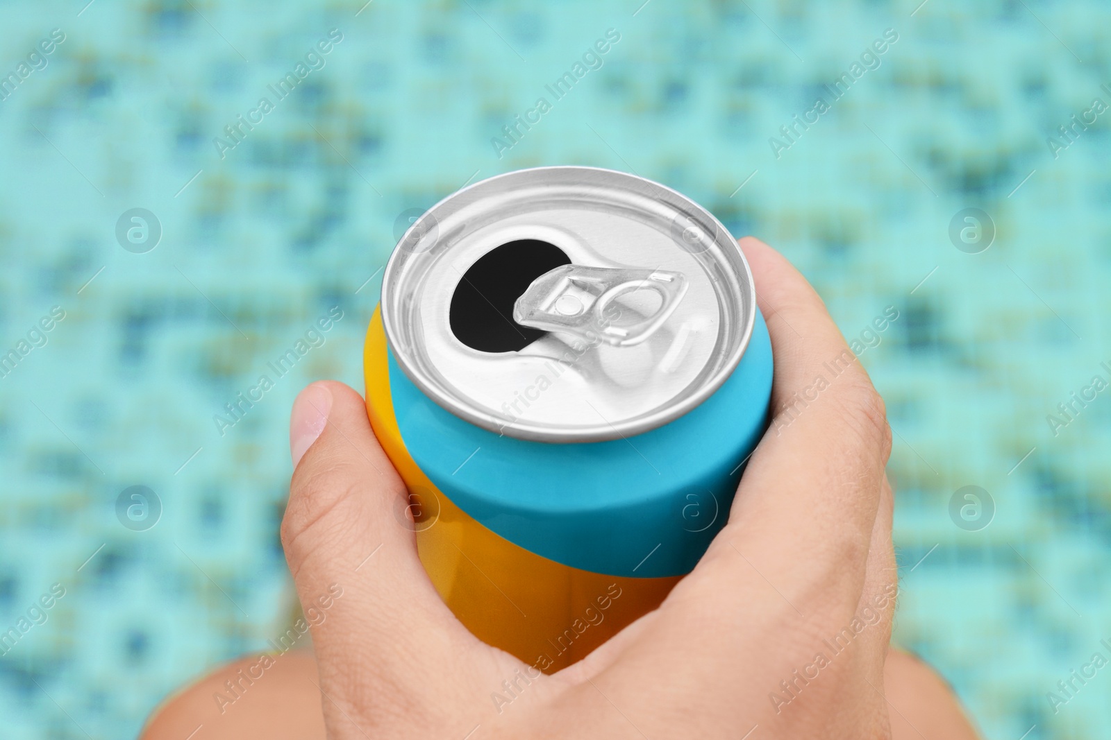 Photo of Woman holding aluminum can with beverage near swimming pool, closeup