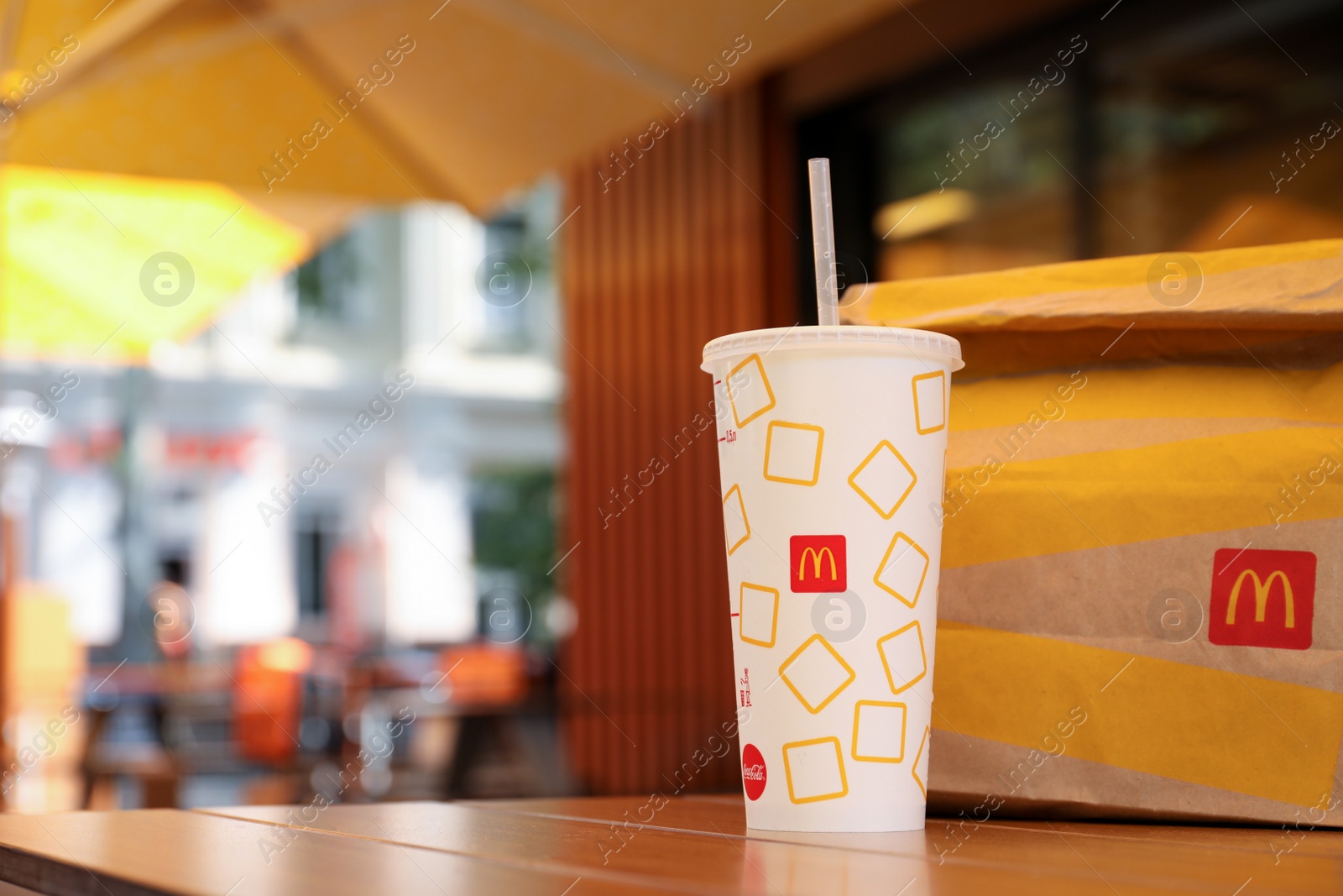 Photo of MYKOLAIV, UKRAINE - AUGUST 11, 2021: Cold McDonald's drink and packed food on table in cafe. Space for text