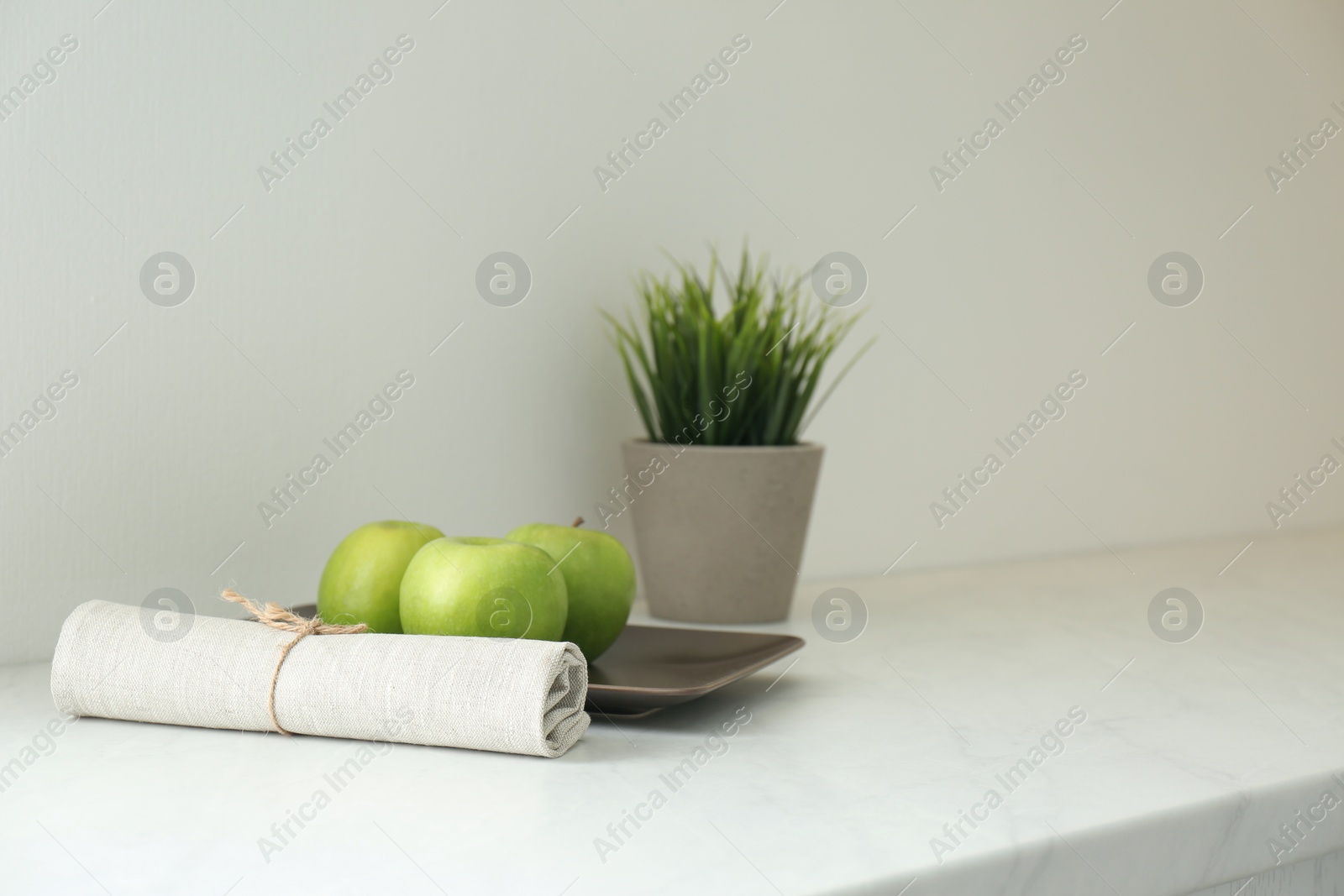 Photo of Fresh apples, napkin and houseplant on countertop in kitchen