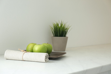 Photo of Fresh apples, napkin and houseplant on countertop in kitchen