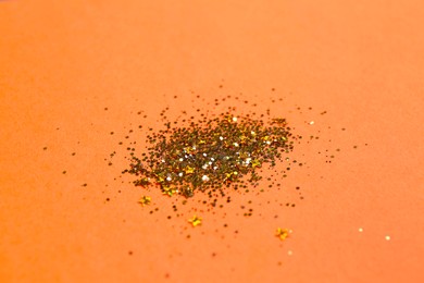 Photo of Shiny bright golden glitter on pale coral background, closeup