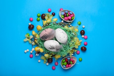 Flat lay composition with candies and eggs on light blue background. Easter celebration