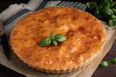 Delicious pie with meat and basil on wooden table