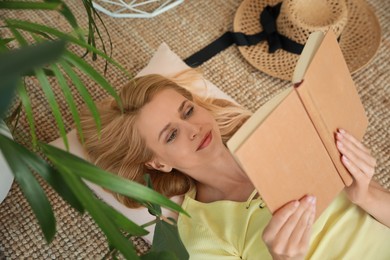 Happy young woman reading book on floor at indoor terrace