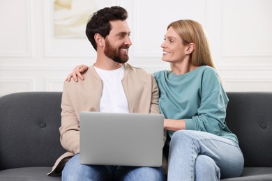 Happy couple with laptop on sofa at home