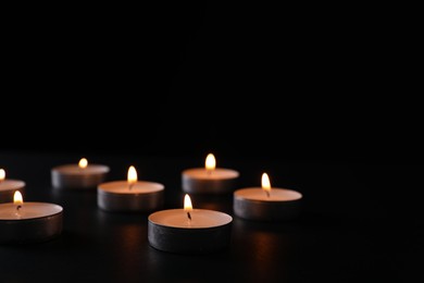 Photo of Burning candles on black background, space for text. Holocaust memory day