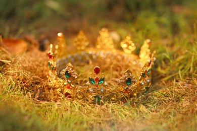 Photo of Beautiful golden crown on fresh green grass outdoors, closeup. Fantasy item