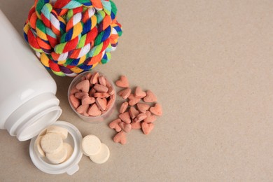 Photo of Different pet vitamins and toy on beige background, flat lay. Space for text