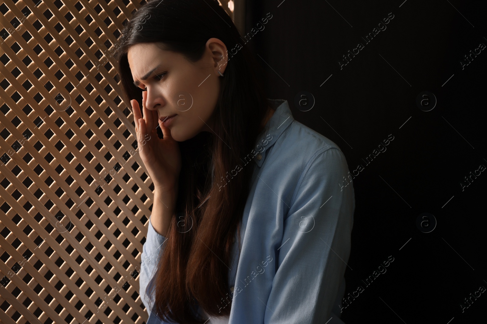 Photo of Upset woman listening to priest during confession in booth