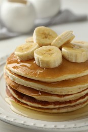 Photo of Delicious pancakes with bananas and honey on white table, closeup