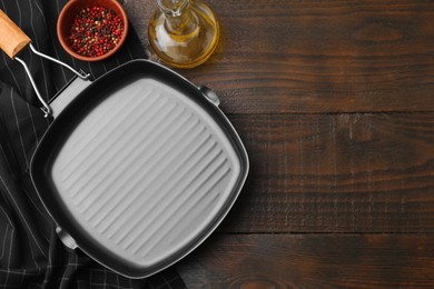 Photo of Grill frying pan, oil and spices on wooden table, flat lay with space for text. Cooking utensils