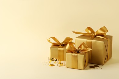 Beautifully wrapped gift boxes and confetti on beige background, space for text