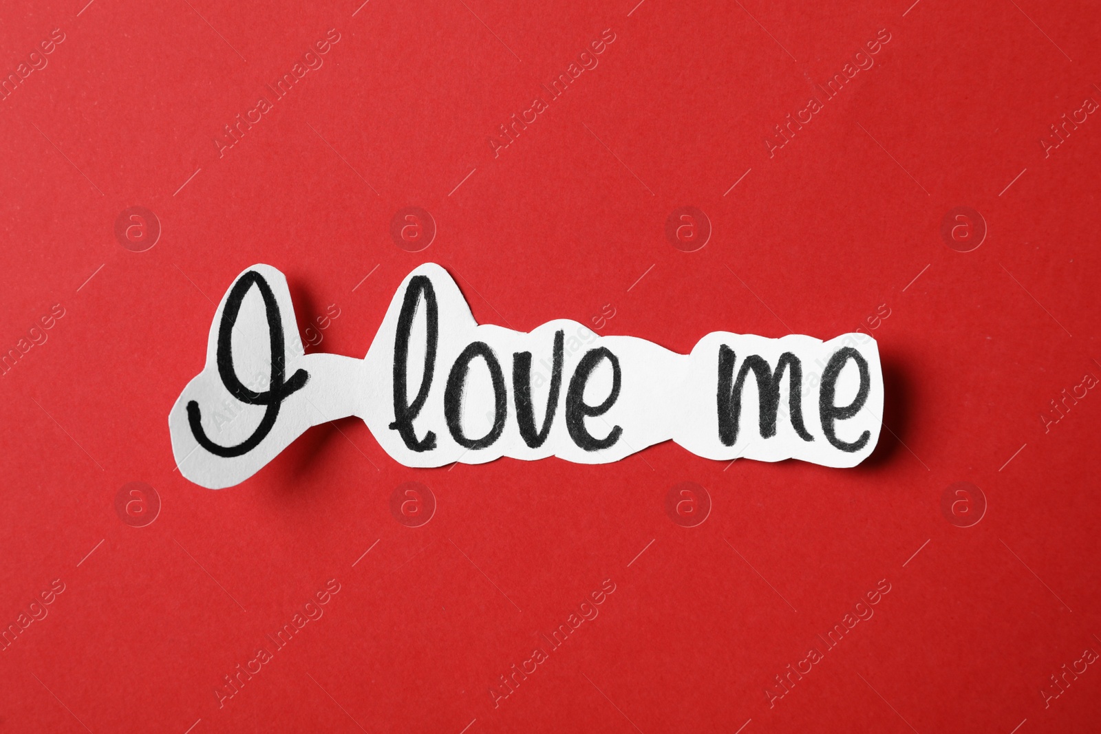 Photo of Piece of paper with handwritten phrase I Love Me on red background, top view