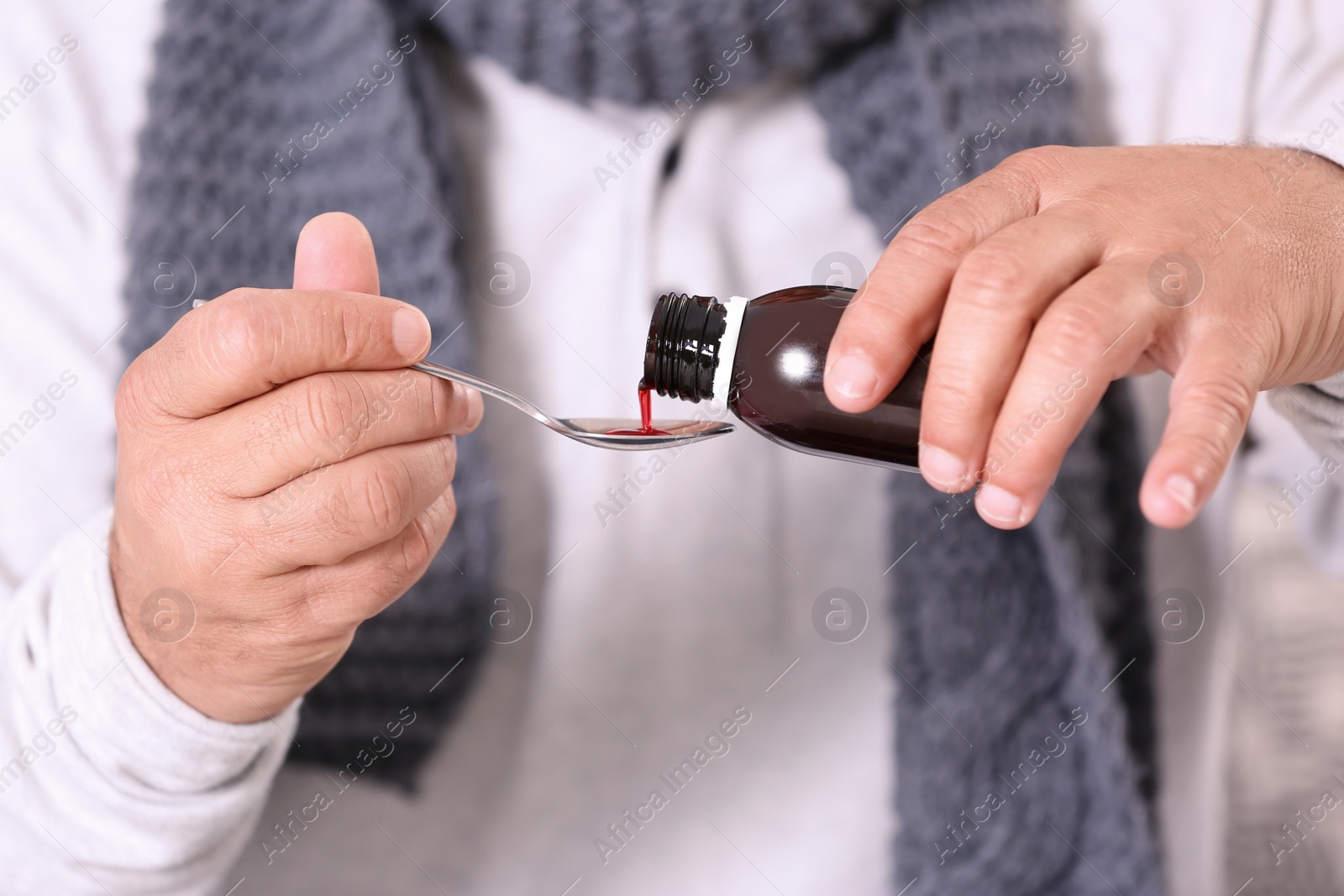 Photo of Senior man taking cough syrup, closeup view