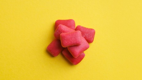 Photo of Sweet chewing gums on yellow background, top view