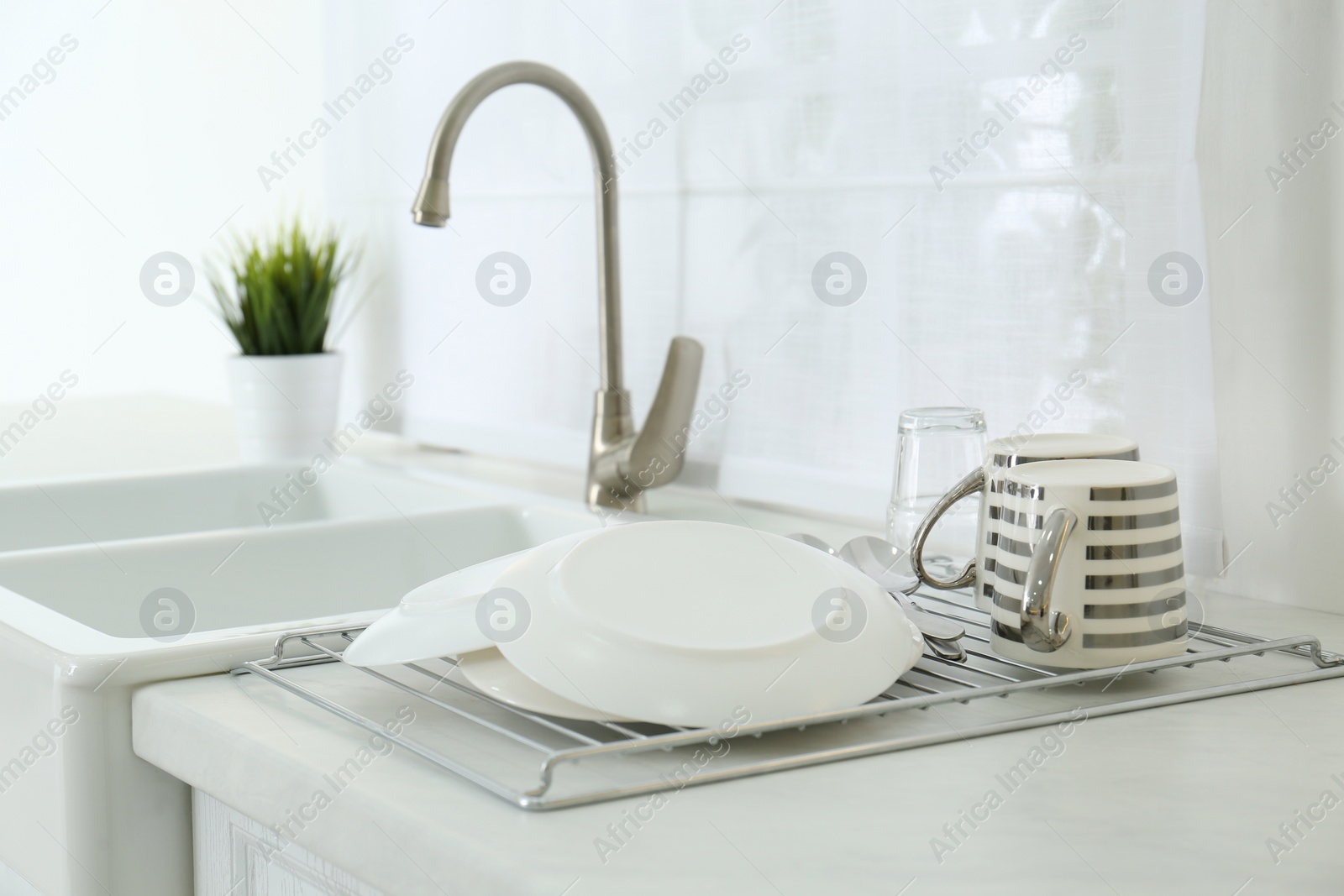 Photo of Clean dishes drying on rack in modern kitchen