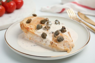 Photo of Delicious chicken fillet with capers and sauce served on white table, closeup