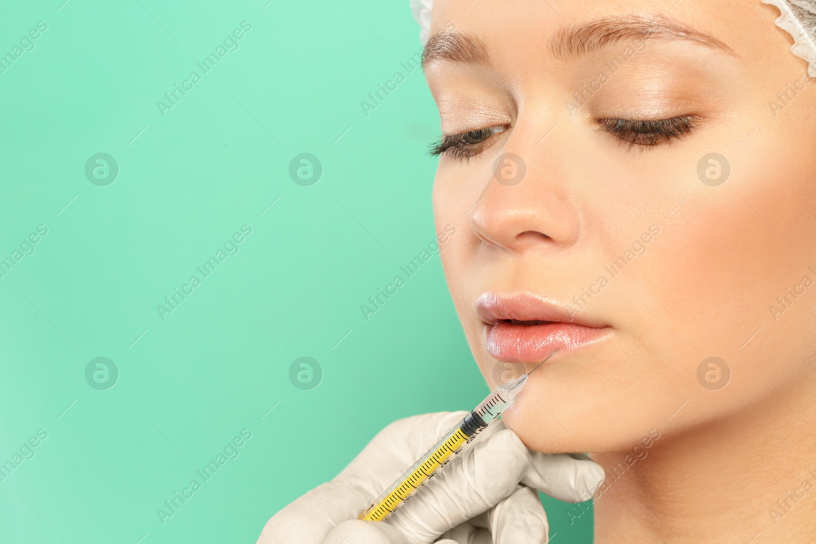 Photo of Young woman getting lips injection on color background, space for text. Cosmetic surgery