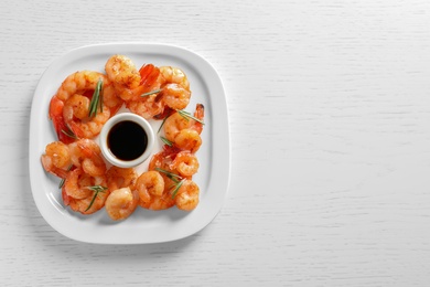 Photo of Plate with delicious fried shrimps and sauce on wooden background