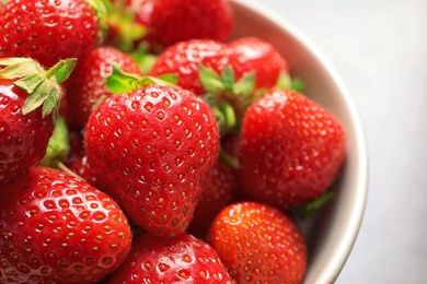 Photo of Bowl with ripe strawberries on grey background, closeup