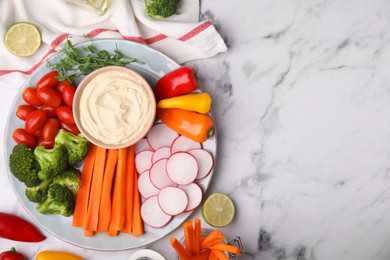 Plate with delicious hummus and fresh vegetables on white marble table, flat lay. Space for text