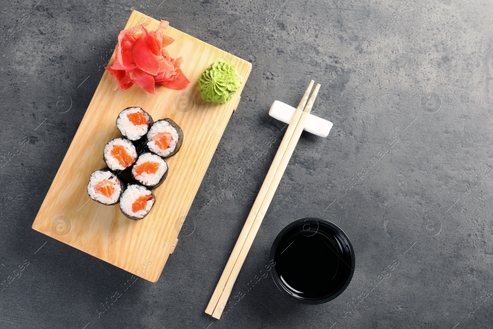 Photo of Tasty sushi rolls on served grey table, top view. Food delivery