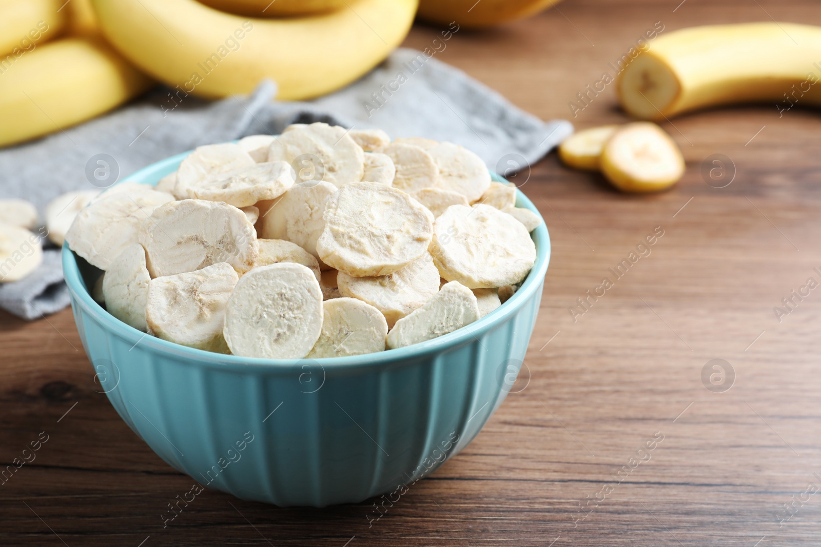 Photo of Freeze dried and fresh bananas on wooden table, closeup. Space for text