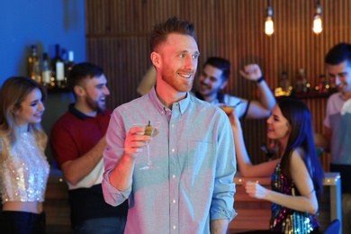 Young man with glass of martini cocktail at party