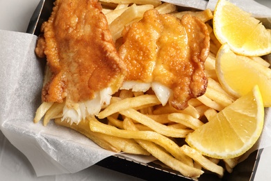 Photo of Container with British traditional fish and potato chips, closeup