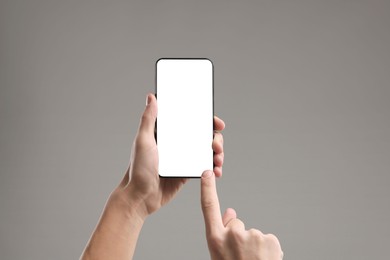 Man using smartphone with blank screen on light grey background, closeup. Mockup for design