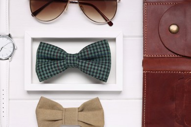Photo of Stylish color bow ties, sunglasses, wallet and wristwatch on white wooden background, flat lay