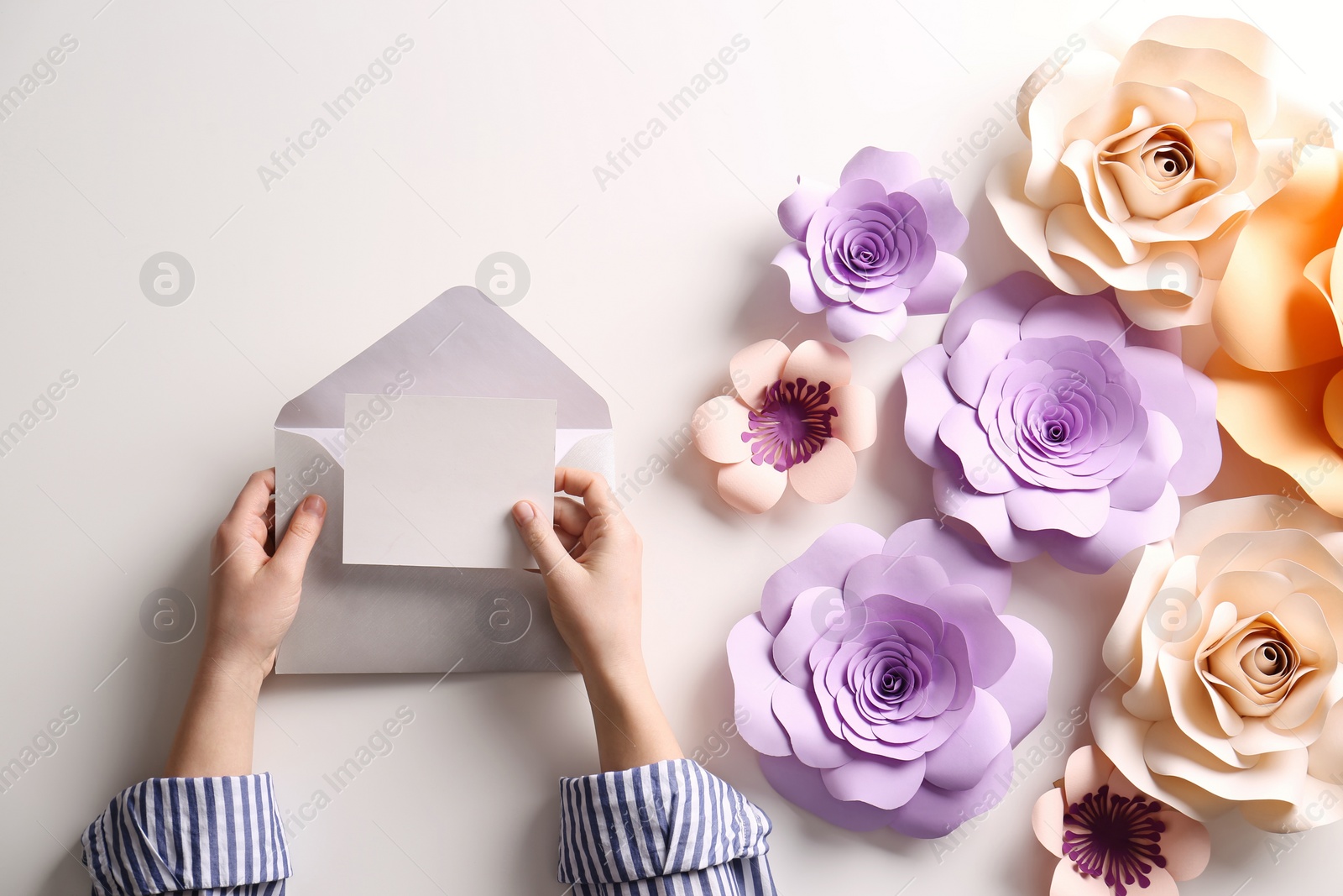 Photo of Woman holding envelope with blank greeting card at table, top view